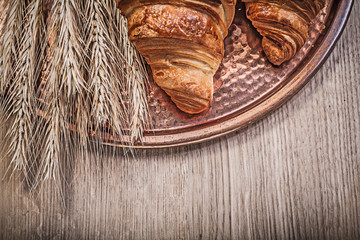 Composition of wheat rye ears fresh-baked croissants copper tray