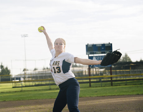 Caucasian softball player pitching ball in field
