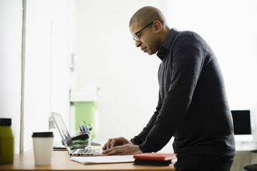 Mixed race businessman working on laptop at desk