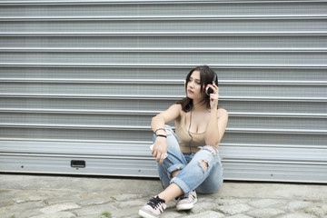 Obraz premium Young beautiful woman sitting down and listening music with head