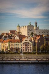 Fototapeta na wymiar White castle with towers and green roofs and red roofs of residential and office houses and river in Szczecin, Poland