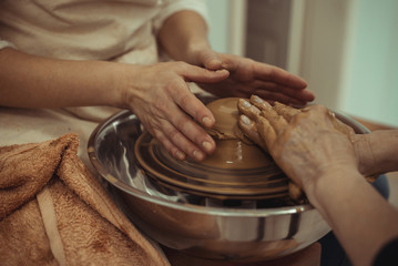 teacher and student work on the potter's wheel