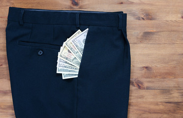  trousers and dollars in the pocket on old wooden table