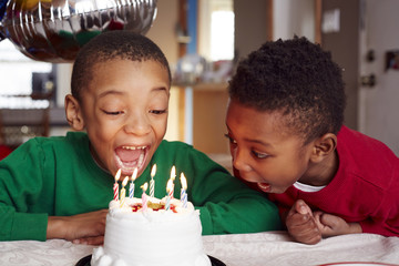 Boys blowing out birthday cake candles at party