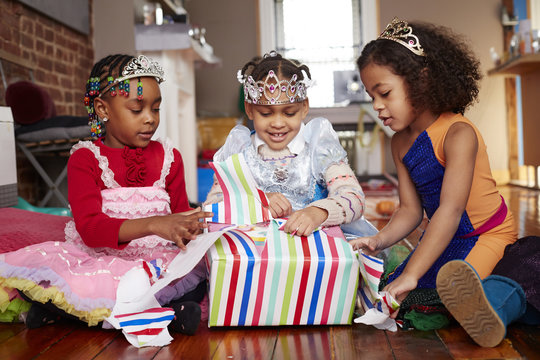 Girls with tiaras opening gift at party