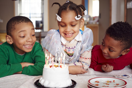 Smiling children admiring cake at party