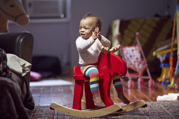 Mixed race baby girl playing on rocking horse