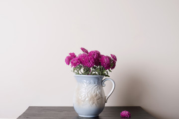 Pink chrysanthemum  in a clay rarity vase on a wooden table, light background