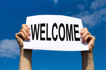 welcome concept, hands holding paper sign on blue sky