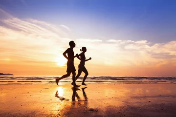 Abwaschbare Fototapete Joggen Sport und gesunder Lebensstil, zwei Leute joggen bei Sonnenuntergang am Strand