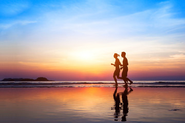 workout background, two people jogging on the beach at sunset, runners silhouettes, healthy...