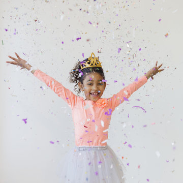Mixed race girl wearing tiara throwing confetti