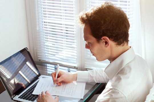 businessman working with documents, reading contract or filling tax form in the office near computer