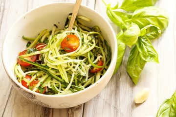 Zucchini pasta noodles with dressing in a white bowl