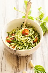 Zucchini pasta noodles with dressing in a white bowl