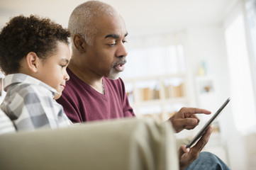 Mixed race grandfather and grandson using digital tablet