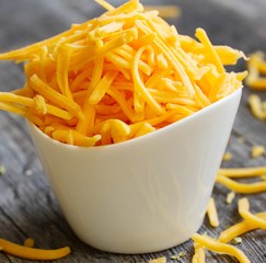 Shredded cheddar cheese in white cup  close up view