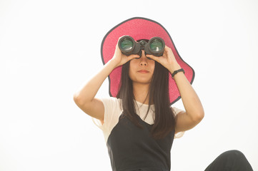 Pretty Asian young  woman sitting on mound seeking binoculars .