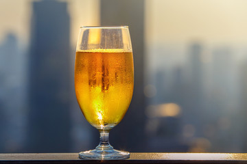 Glass of beer against blurred asian city with beautiful lights on background at evening
