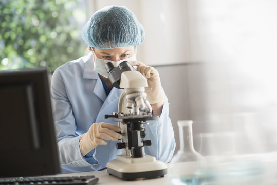Mixed race scientist using microscope in laboratory
