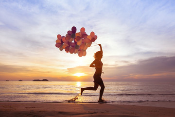 happiness concept, psychology of happy people, young woman running with multicolored balloons on the beach