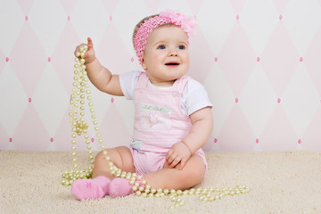 Little girl sitting on the floor holding pearl necklace