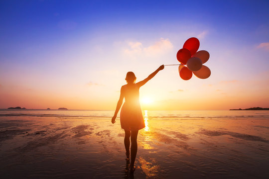 happiness concept, positive emotions, happy girl with multicolored balloons enjoying summer beach at sunset