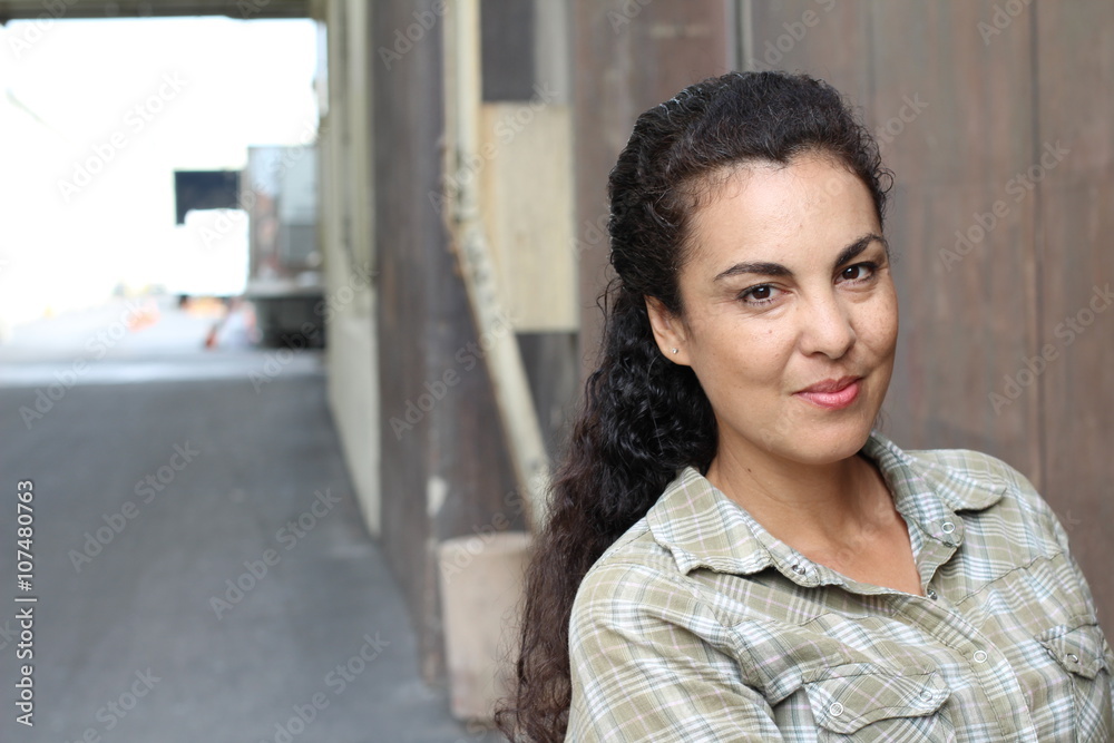 Wall mural beautiful woman in her forties wearing a casual plaid shirt in urban background