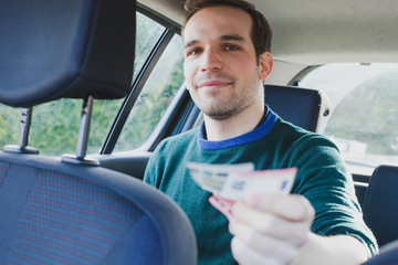 happy passenger in taxi paying by cash