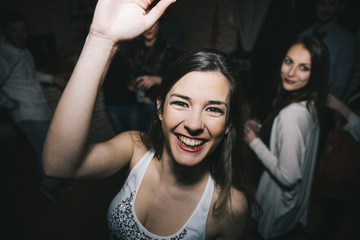 Smiling woman waving in nightclub