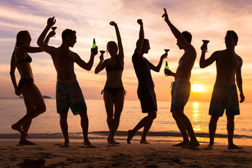 beach party, group of young people dancing, friends drinking beer and cocktails at sunset
