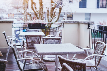 terrace of street cafe in winter, tables and chairs covered by snow