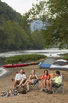 Friends relaxing around campfire at campsite