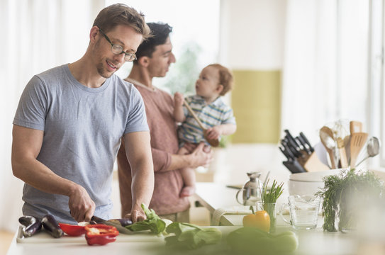 Caucasian gay fathers and baby cooking in kitchen