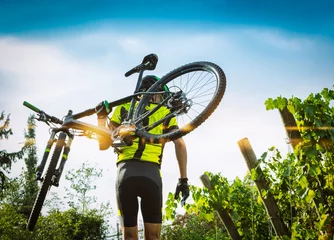 Photo sur Plexiglas Vélo Cyclist raises the mountain bikes on their shoulders.