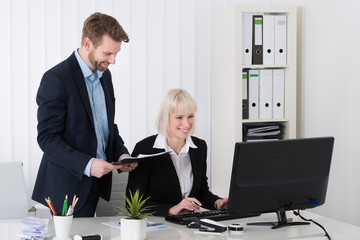 Two Young Businesspeople Working On Computer