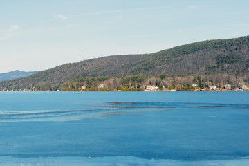 Color DSLR stock image of a frozen Lake George, with lake houses on the shore and Adirondack Mountains in background. Horizontal with copy space for text
