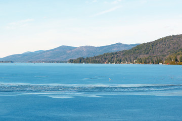 Color DSLR stock image of a frozen Lake George, with lake houses on the shore and Adirondack Mountains in background. Horizontal with copy space for text
