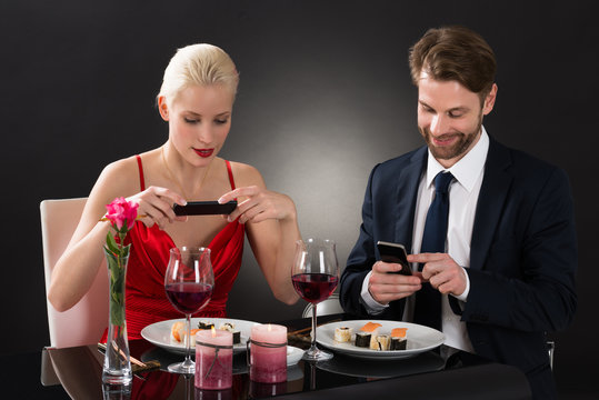 Couple Taking Picture Of Food With Their Smartphone