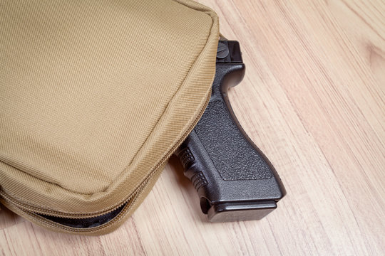 weapon gun in bag, khaki or sand color, on table background