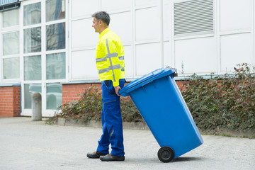 Male Worker Walking With Dustbin On Street