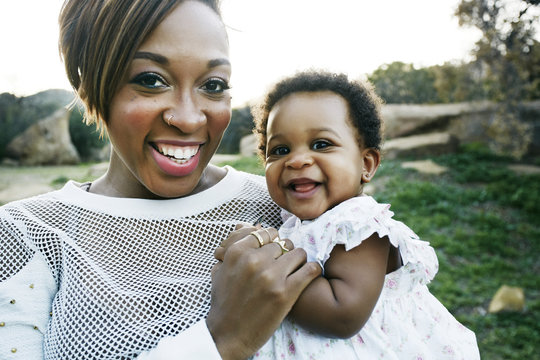Black mother holding baby daughter in field