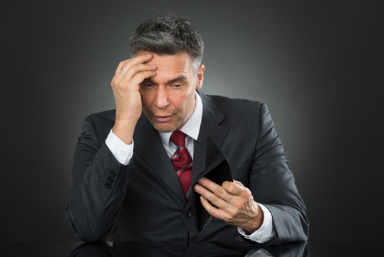 Businessman With Empty Wallet Sitting At Desk