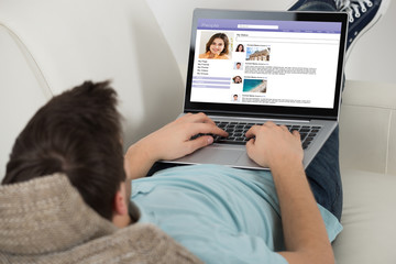 Man Surfing Social Networking Site On Laptop