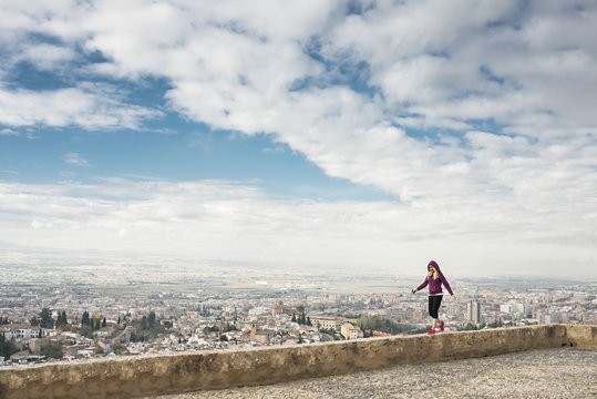 Caucasian woman on wall overlooking scenic view of cityscape, Granada, Spain