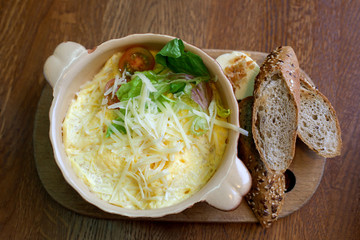 Omelet with cheese and grain bread on kitchen board