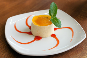 A mousse with passionfruit jam with red syrup on white plate