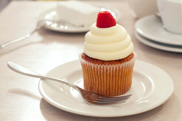 A cupcake with raspberry on the table