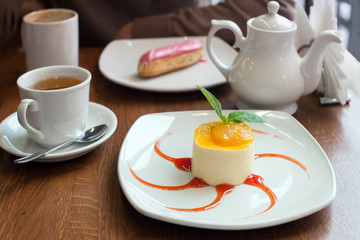 A mousse with passionfruit jam with red syrup and tea on the table