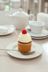 A cupcake with raspberry on the table